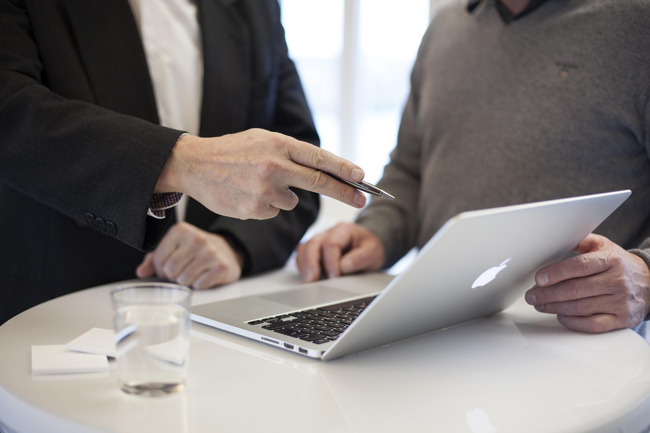 2 people discussing with a laptop on table